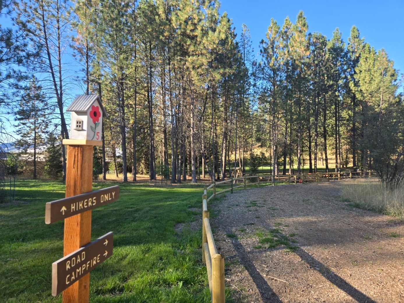 Wooded setting with split-rail fencing and trail and campfire signs